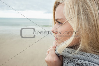 Cute young woman in gray knitted jacket on beach