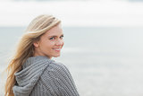 Cute young woman in gray knitted jacket on beach