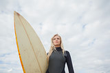Beautiful woman with surfboard against cloudy sky