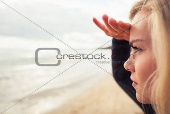 Side view of a beautiful blond shielding eyes at beach
