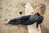 Smiling beautiful blond in wet suit with surfboard at beach