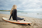 Smiling beautiful blond in wet suit with surfboard at beach