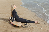 Beautiful blond in wet suit with surfboard at beach