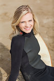 Portrait of a beautiful blond in wet suit with surfboard