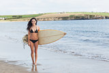 Full length of bikini woman holding surfboard at beach