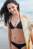 Smiling bikini woman holding surfboard at beach
