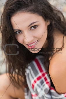 Smiling young woman covered with blanket at beach