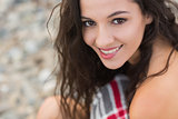 Smiling young woman covered with blanket at beach