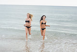 Smiling bikini women running in water at beach