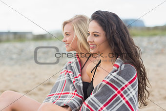 Young women covered with blanket at beach