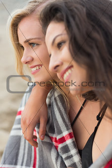 Two young women covered with blanket at beach