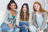 Female friends using digital tablet together on sofa