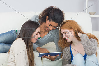 Female friends using digital tablet together at home