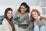 Female friends using digital tablet together at home