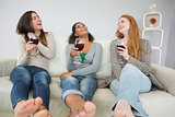 Cheerful young female friends with wine glasses at home