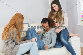 Cheerful young female friends enjoying on sofa