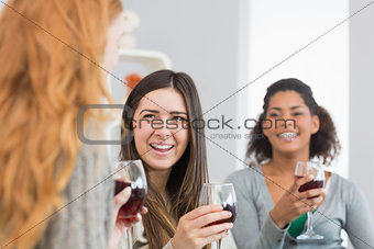 Cheerful friends with wine glasses enjoying a conversation at home
