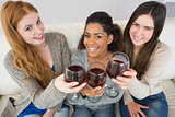 Cheerful young female friends toasting wine glasses