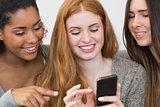 Close up of happy friends pointing at mobile phone together
