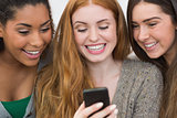 Close up of cheerful friends looking at mobile phone together