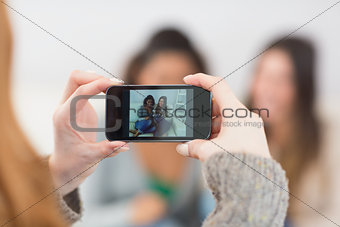 Close up of a woman photographing friends with smartphone