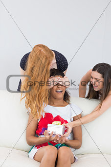 Cheerful young women surprising friend with a gift