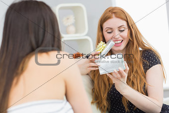 Young woman surprising blond friend with a gift