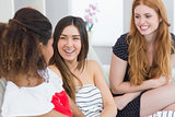 Cheerful young female friends chatting on sofa