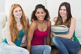 Portrait of young female friends on floor against sofa