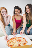 Happy female friends eating pizza at home