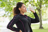 Tired healthy woman drinking water in the park