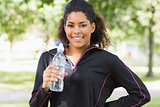 Portrait of a smiling woman with water bottle in park
