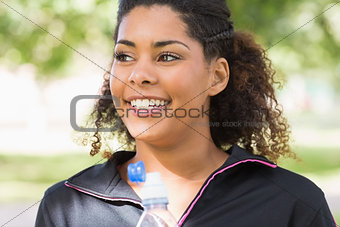 Close up of a smiling tired woman with water bottle in park