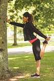 Healthy woman stretching her leg during exercise at park