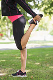 Side view of woman stretching her leg during exercise at park