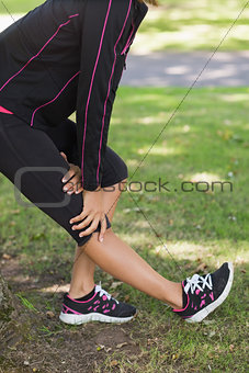 Mid section of woman stretching her leg during exercise at park