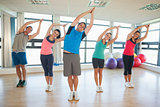 Fitness class and instructor standing in Namaste position