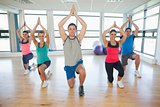 Fitness class and instructor kneeling in Namaste position