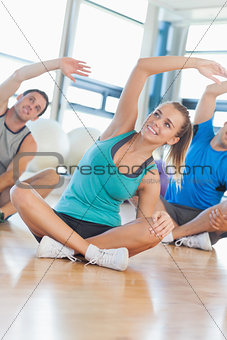Fitness class and instructor sitting and stretching hands