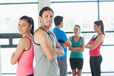 Fit couple with friends standing in background in exercise room