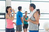 Fit couple with friends in background in exercise room
