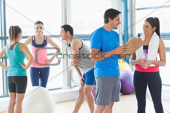 Fit couple with friends in background in exercise room