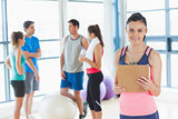 Instructor with fitness class in background in fitness studio