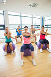 Sporty people stretching hands on exercise balls at gym