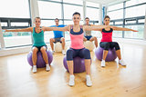 Sporty people stretching out hands on exercise balls at gym