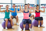 Class exercising with dumbbells on fitness balls
