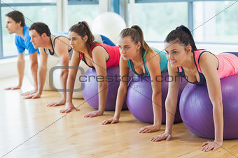 Fitness class exercising on fitness balls in a row