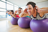 Side view of class exercising on fitness balls in a row