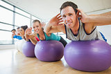 Portrait of class exercising on fitness balls in a row