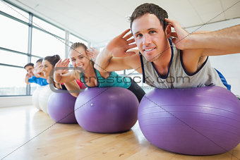 Portrait of class exercising on fitness balls in a row